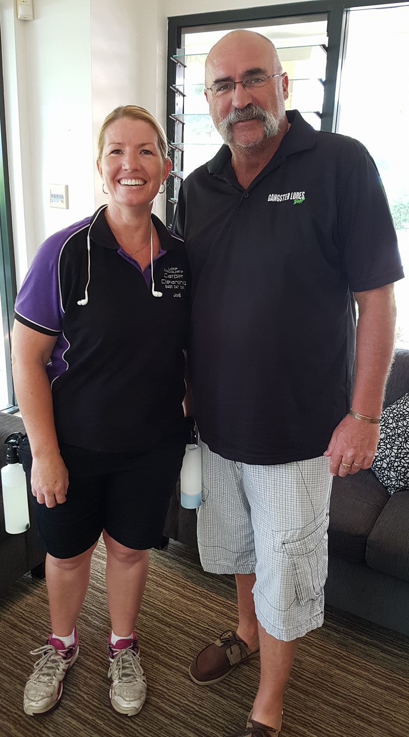 A man and a woman are posing for a picture in a living room. — Lake Macquarie Carpet Cleaning In Warners Bay, NSW