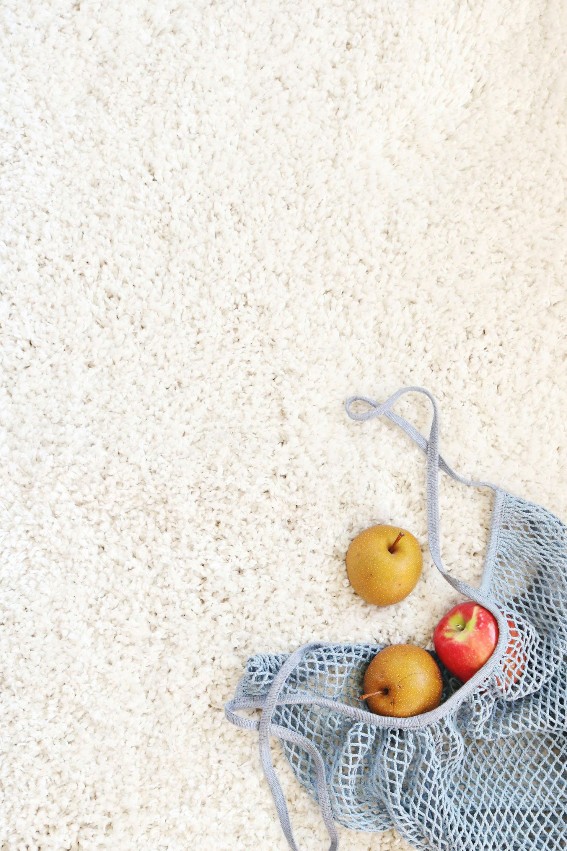 A Man Is Vacuuming A Rug In A Living Room — Lake Macquarie Carpet Cleaning In Swansea, NSW