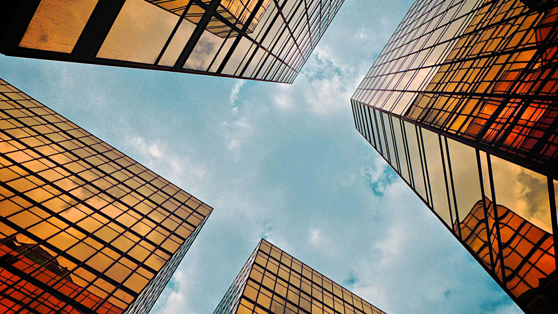Golden skyscrapers, low-angle view against a partly cloudy sky.