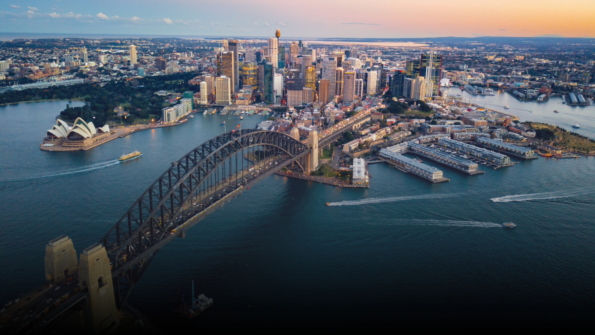Sydney Harbour with the Harbour Bridge in the foreground, city skyline in the background, and water surrounding.