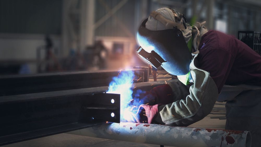 A Man Is Welding a Piece of Metal in A Factory — FBM Fabrication In Wollongong, NSW