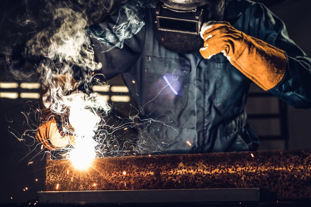 A Man Is Welding a Piece of Metal in A Factory — FBM Fabrication In Dapto, NSW