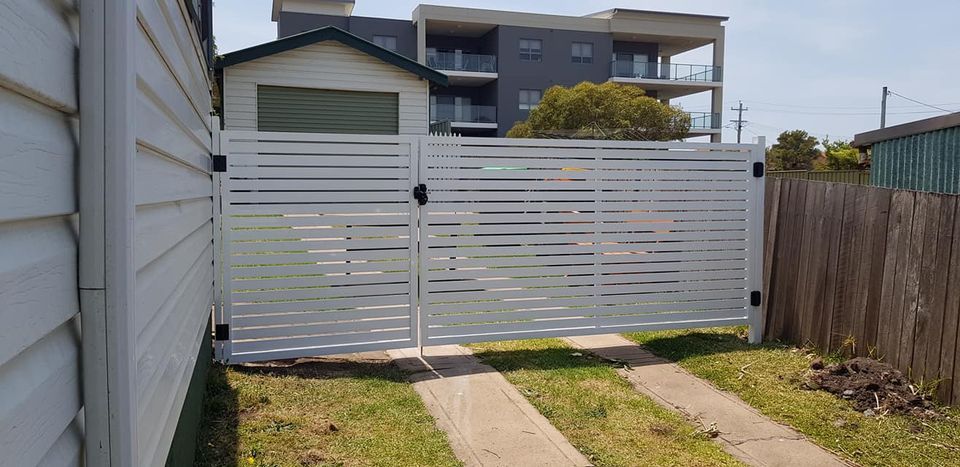 A Person Is Holding a Remote Control in Front of A Sliding Gate — FBM Fabrication In Dapto, NSW
