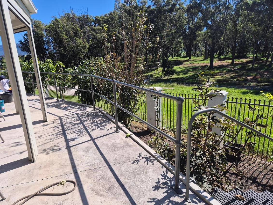 Patio railing overlooking a sunny green yard with trees and a fence — FBM Fabrication In Dapto, NSW