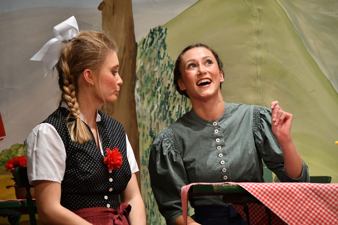 Zwei Schauspielerinnen der Theatergruppe Emmering auf der Bühne reden an einem Tisch im Stück 