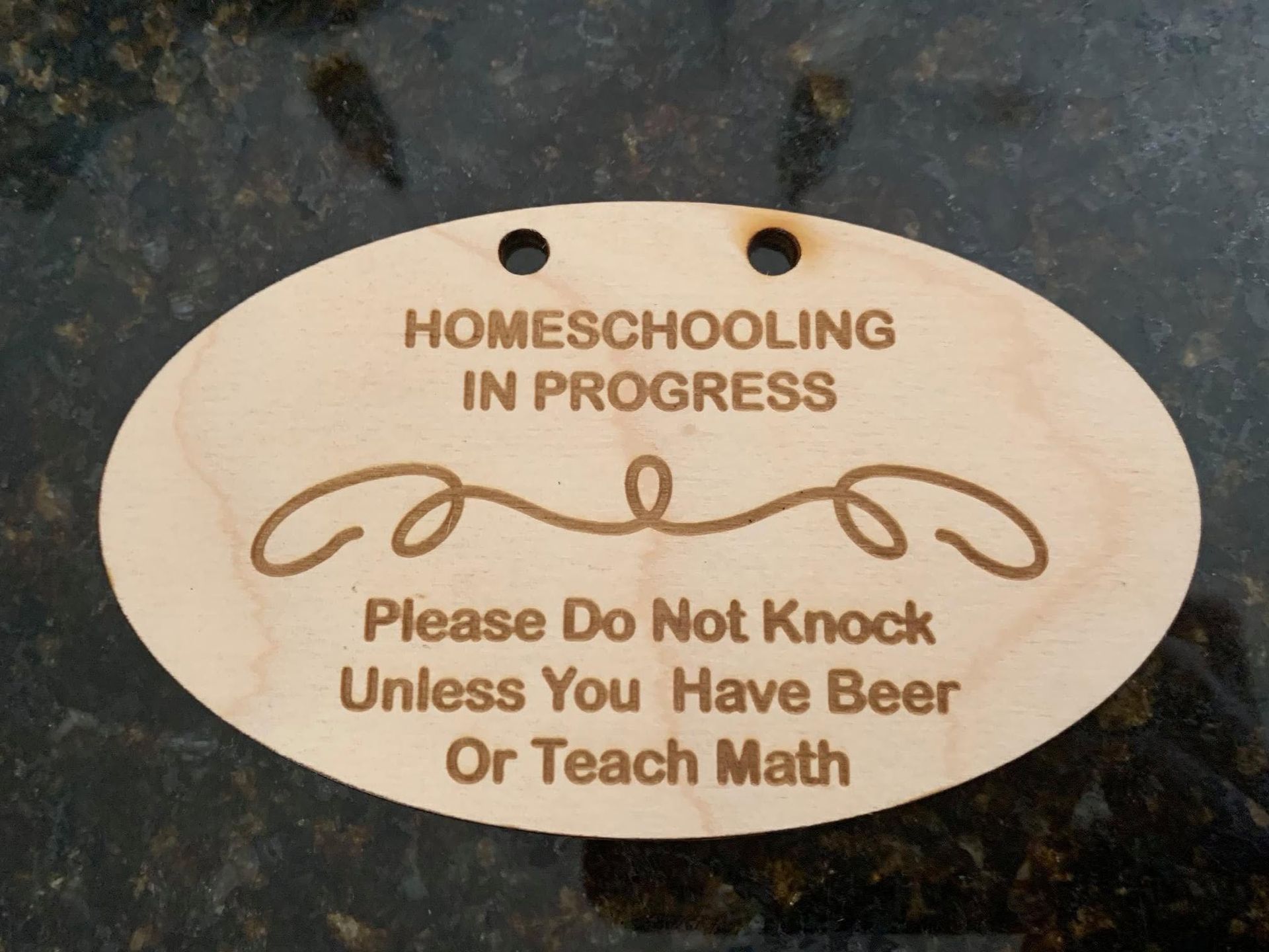 A light-wood oval sign that reads 