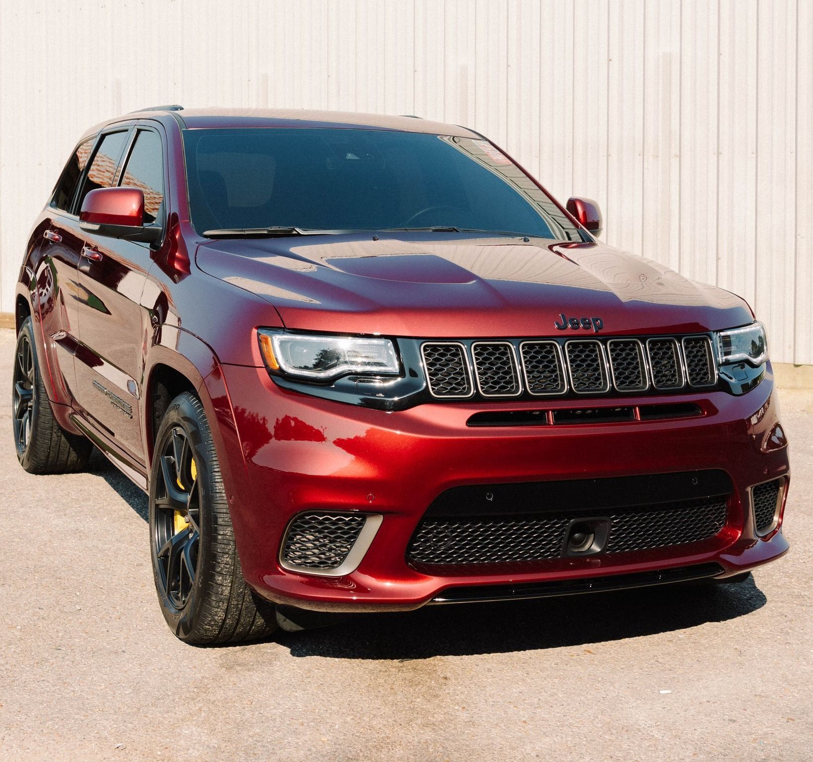 A red jeep grand cherokee is parked in front of a white building.