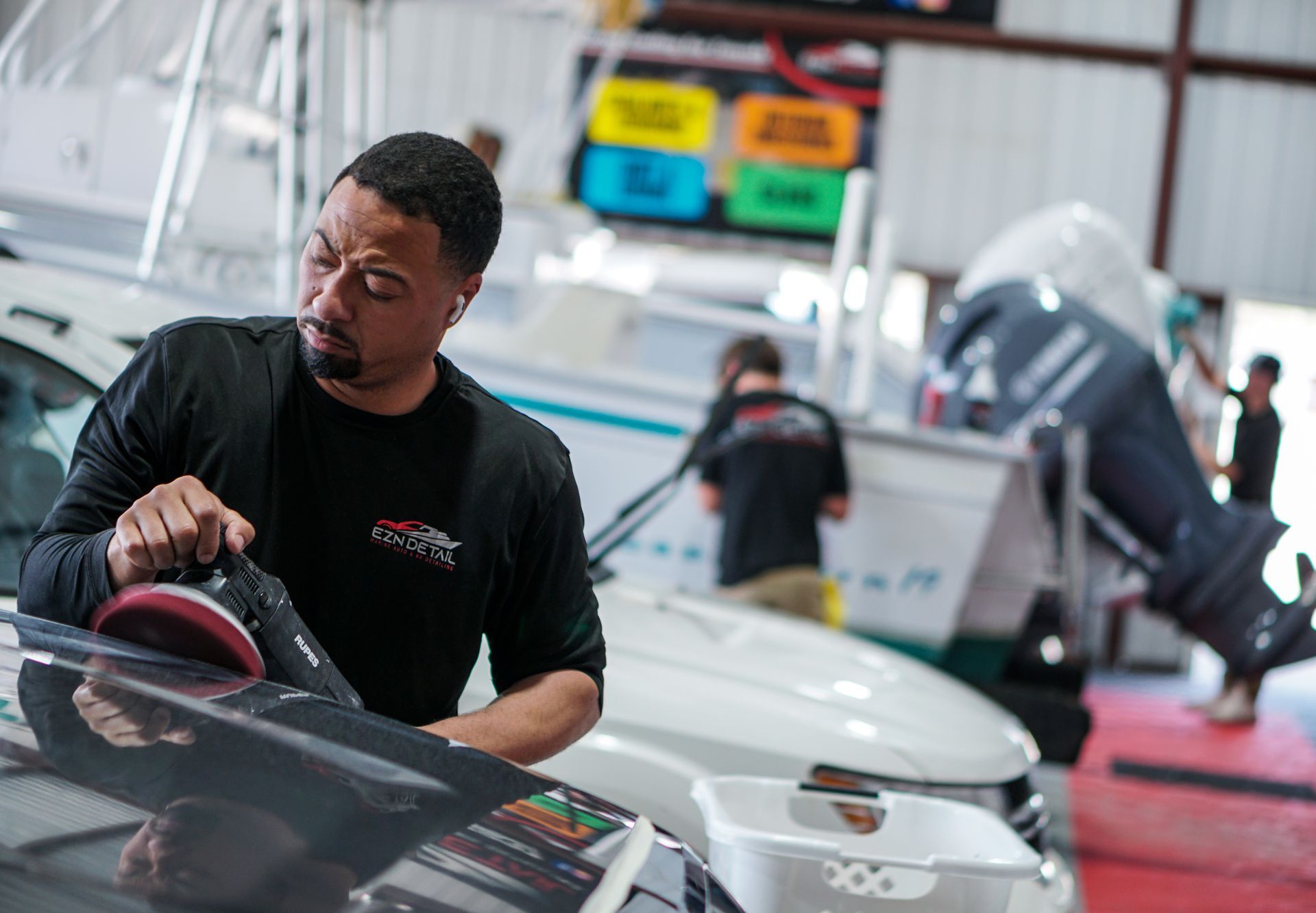 A man is polishing the hood of a car in a garage.