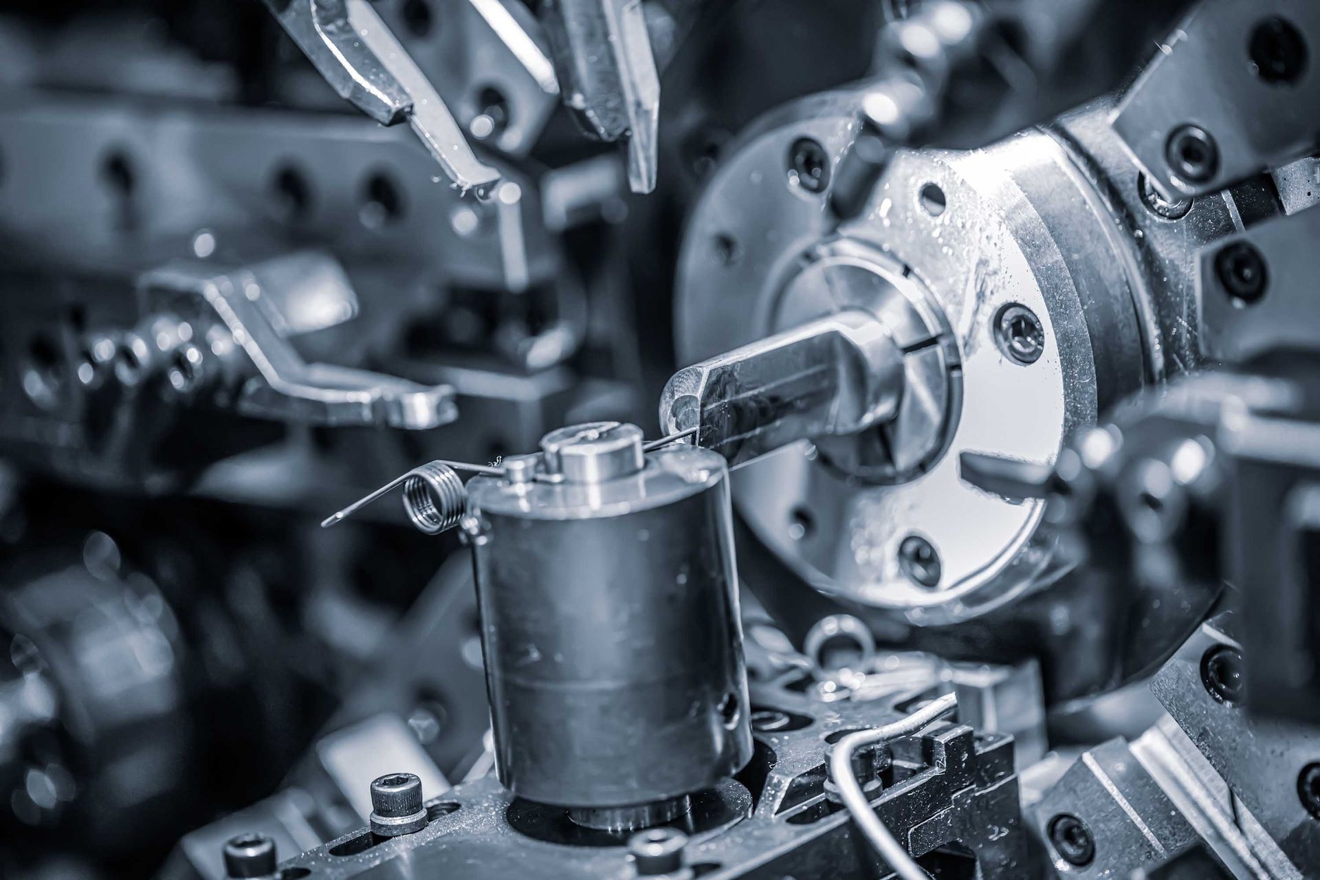 Gros plan sur une machine à fabriquer des ressorts métalliques en fonctionnement, coupant et façonnant des pièces métalliques.