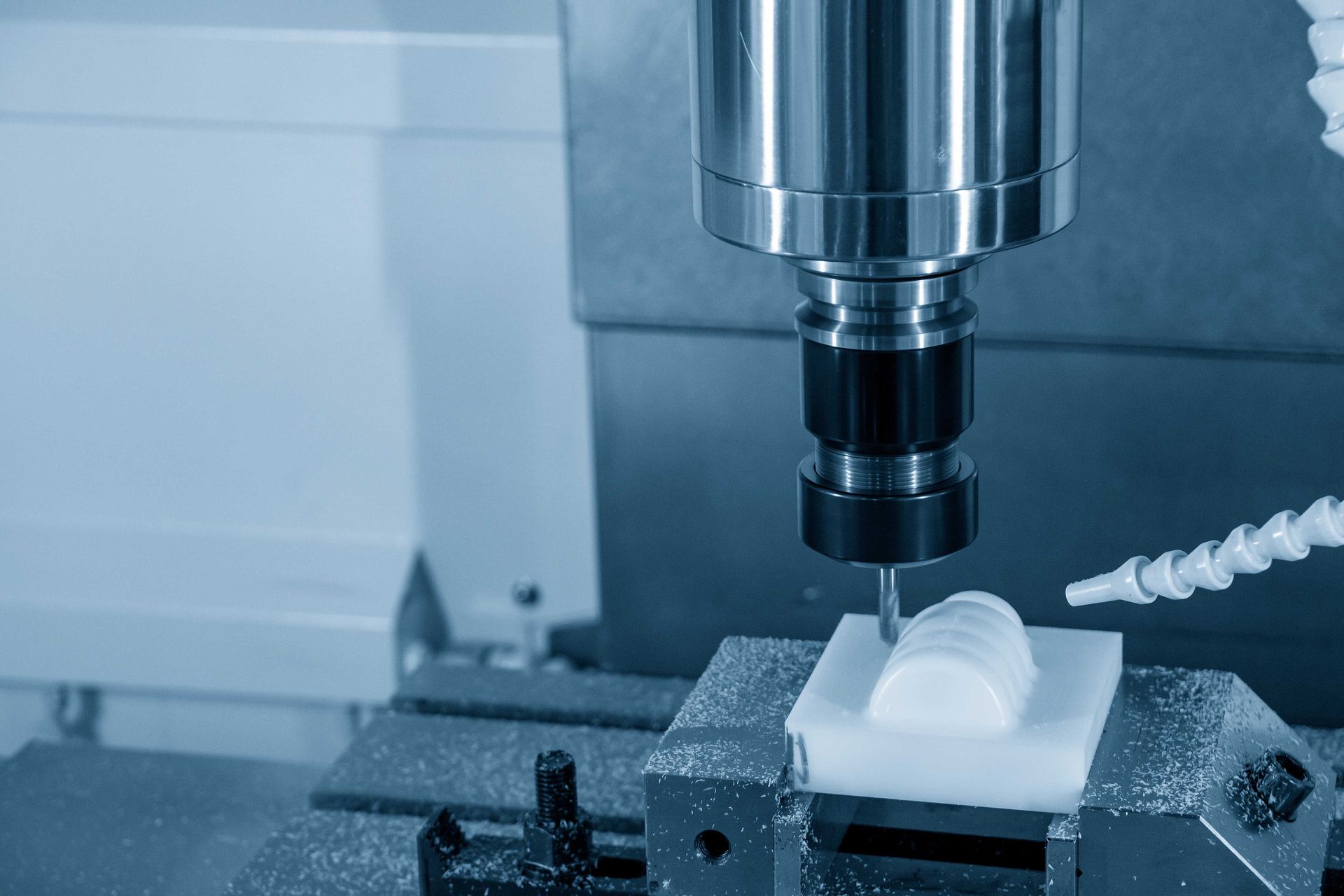 Machine de fraisage CNC découpant une pièce en plastique blanc.