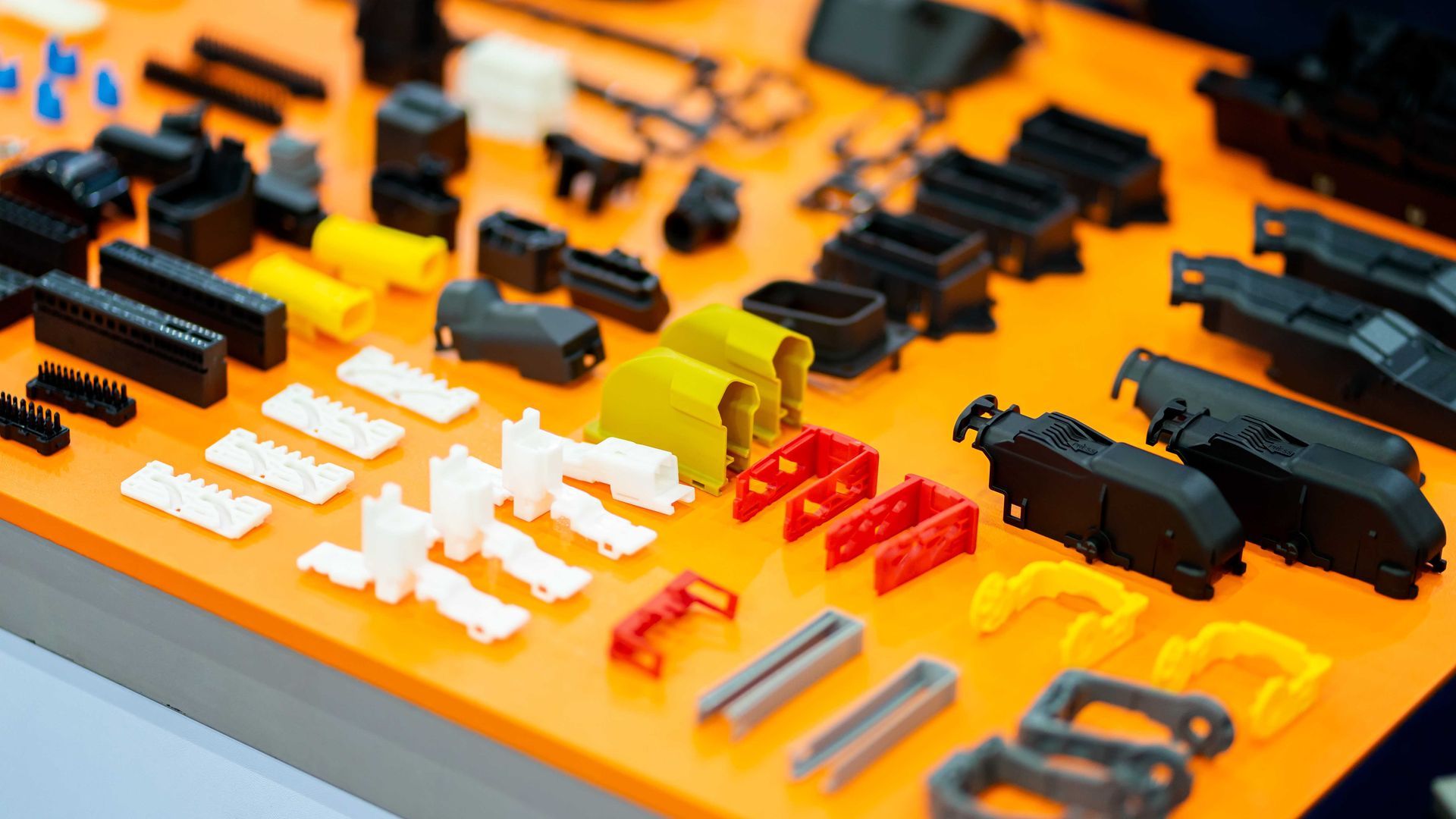 Diverses pièces en plastique noires, blanches, jaunes et rouges sur une surface orange.
