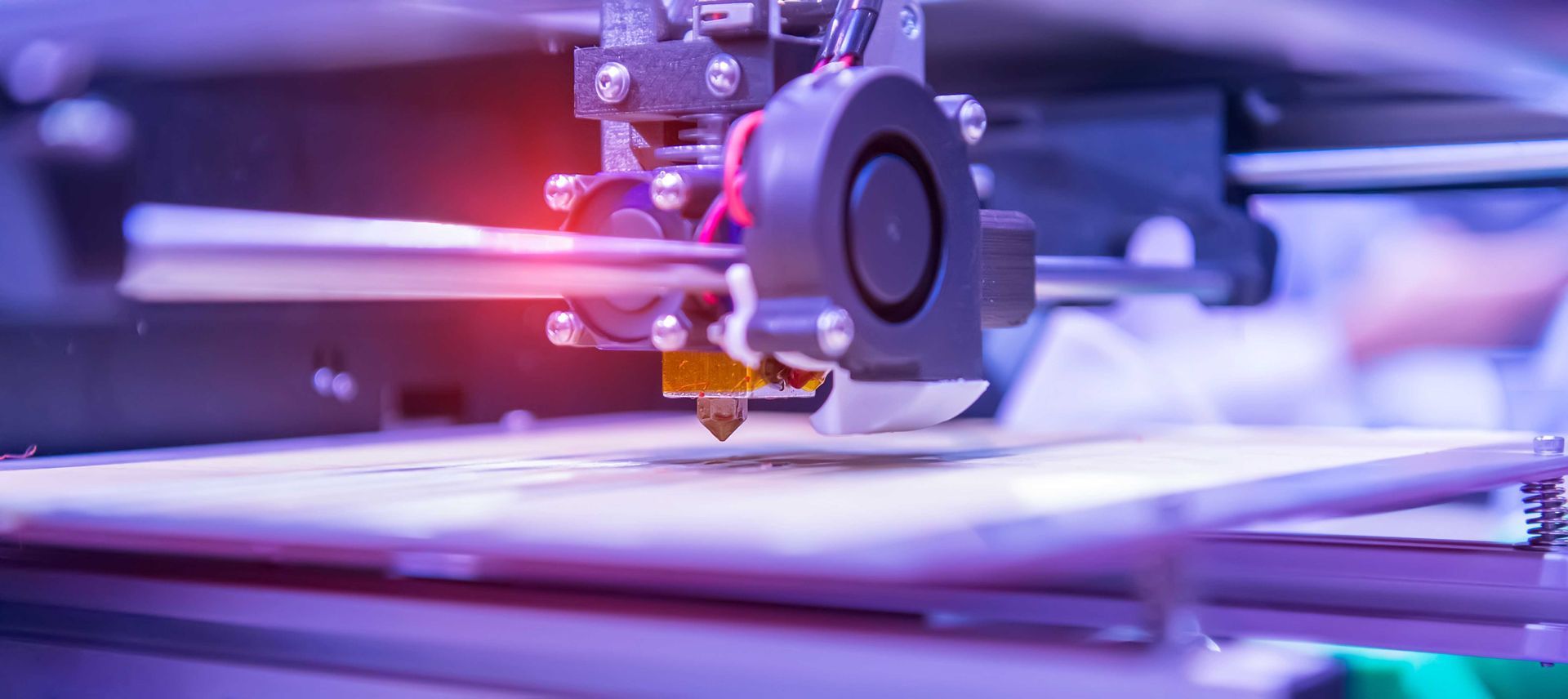 Une tête d'imprimante 3D dépose du matériau sur une base blanche, créant ainsi une couche.