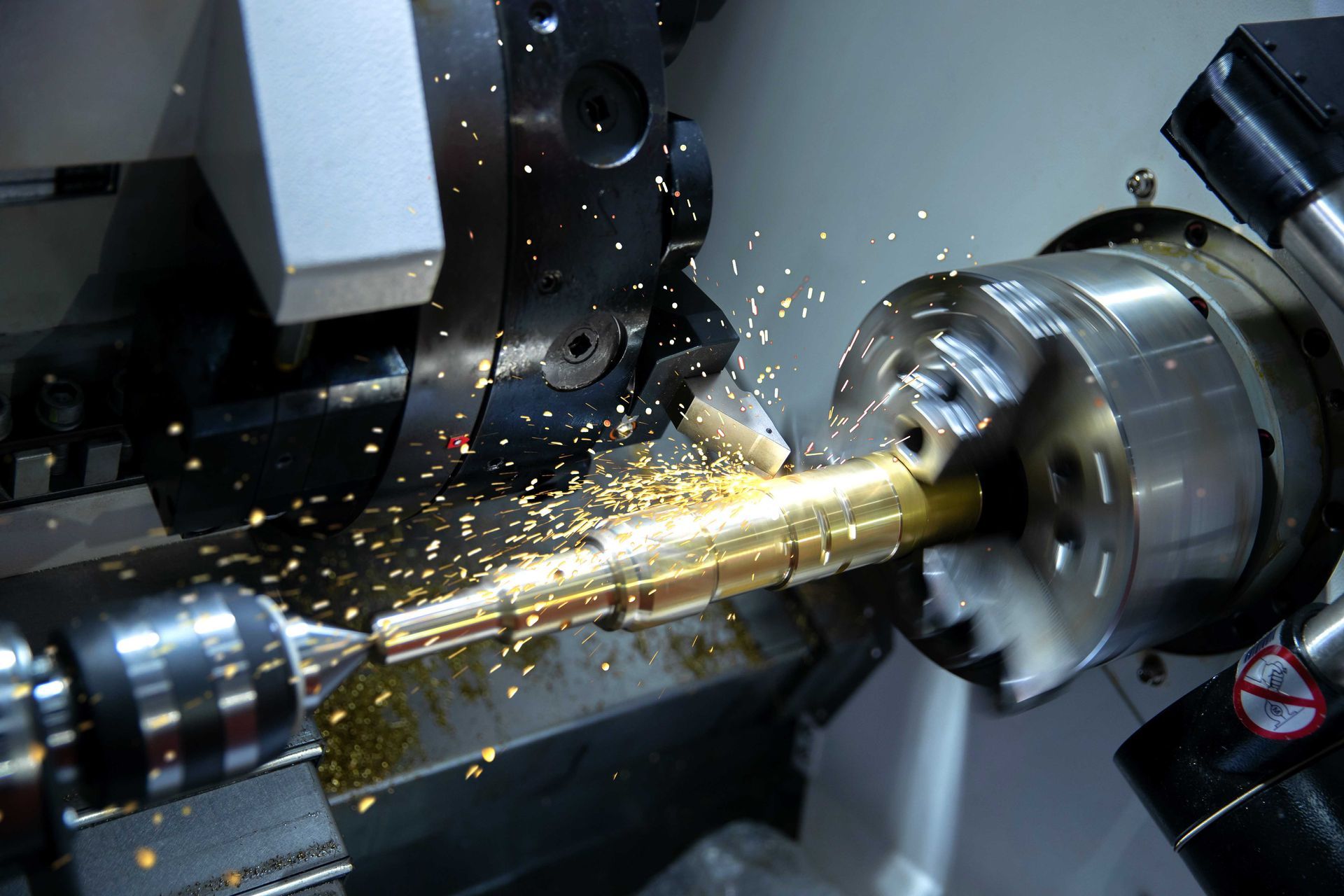 Tour CNC coupant une tige de laiton, produisant des copeaux de métal.