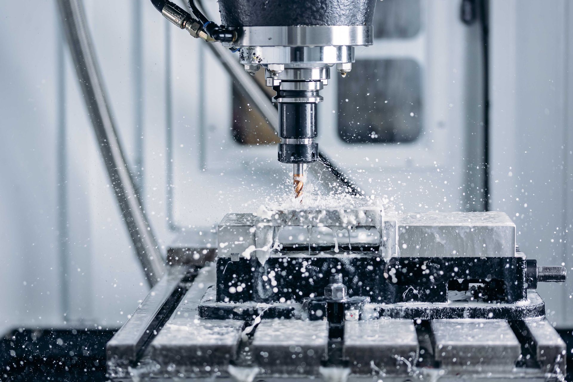 Machine CNC de découpe de métal, projection de copeaux et de liquide de refroidissement.