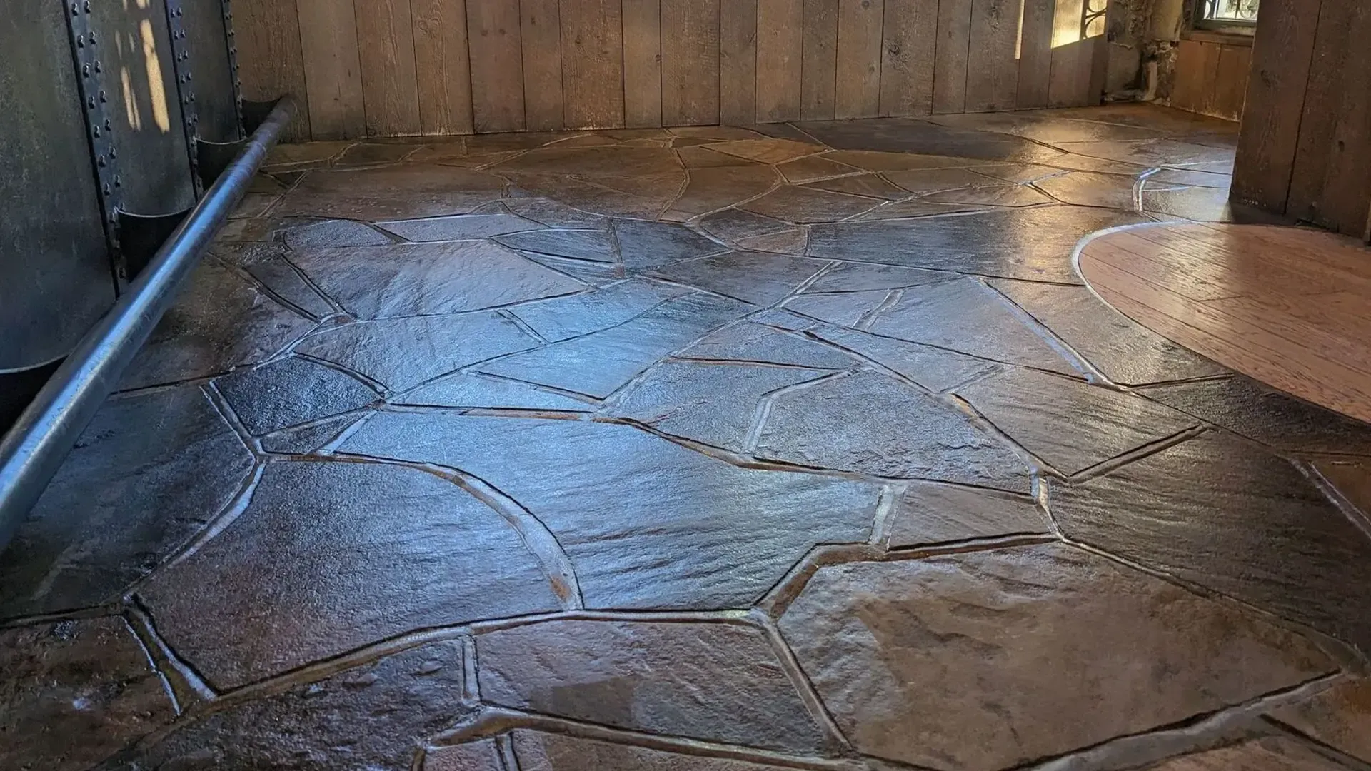 Stone-like patterned floor in a room with wood panel walls and a visible metal structure.