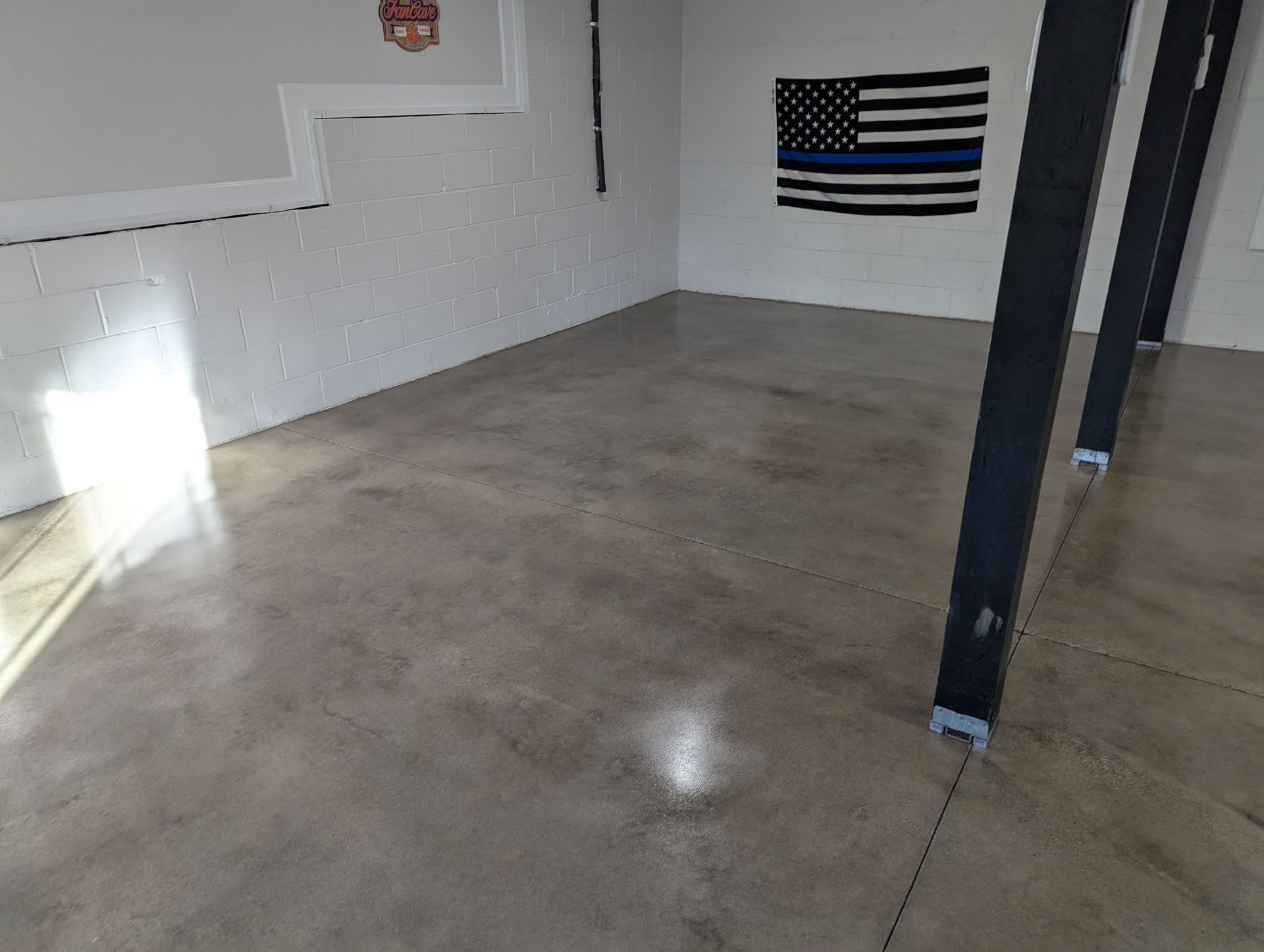A room with a flag on the wall and a concrete floor.