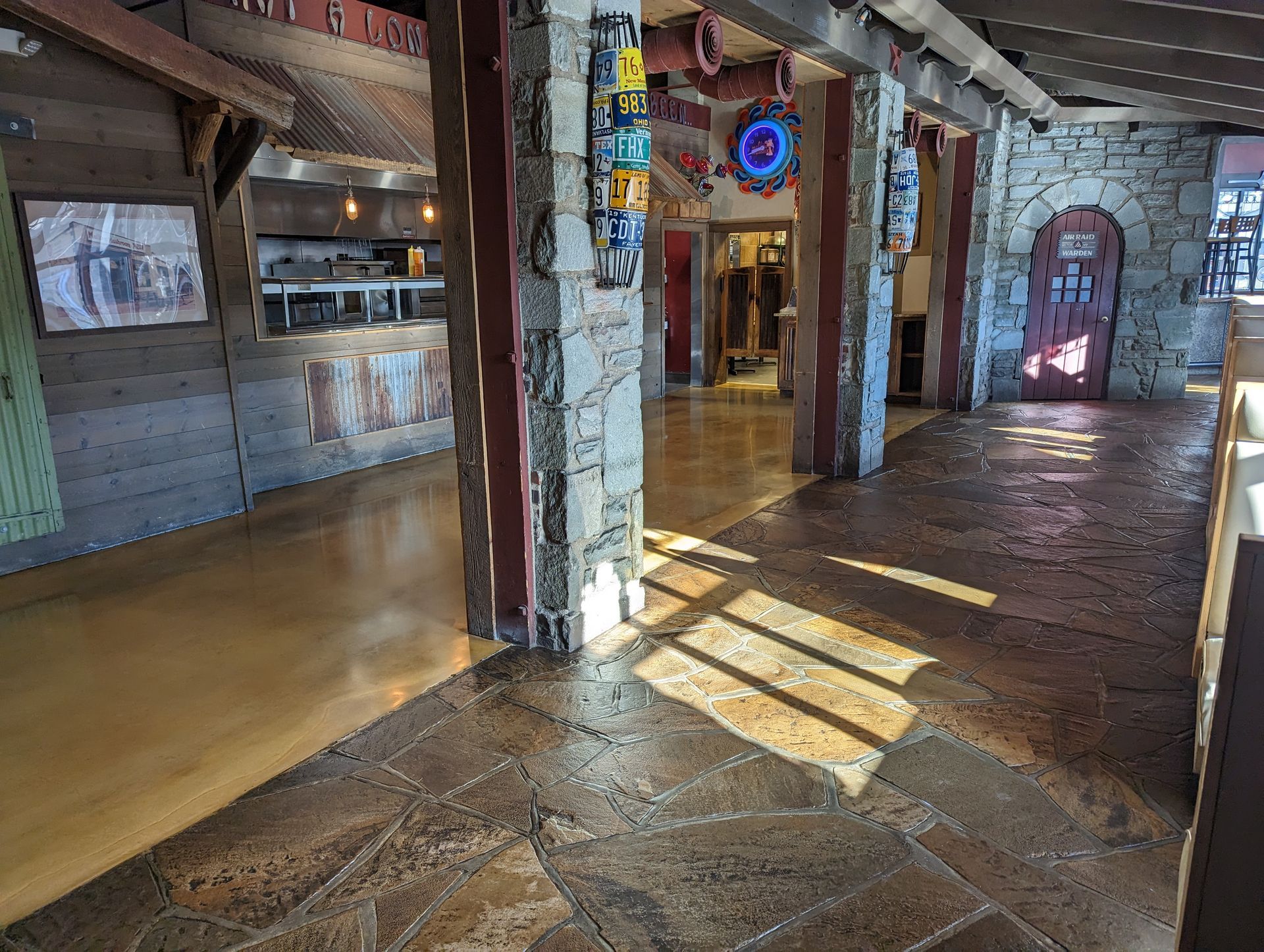 A long hallway in a building with a stone floor and pillars.