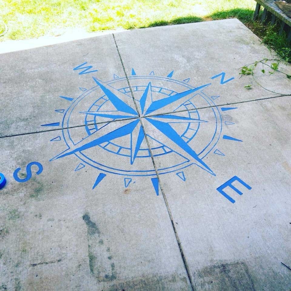 A blue compass is engraved on a concrete surface