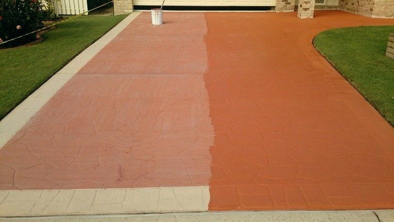 A driveway is being painted red and white.