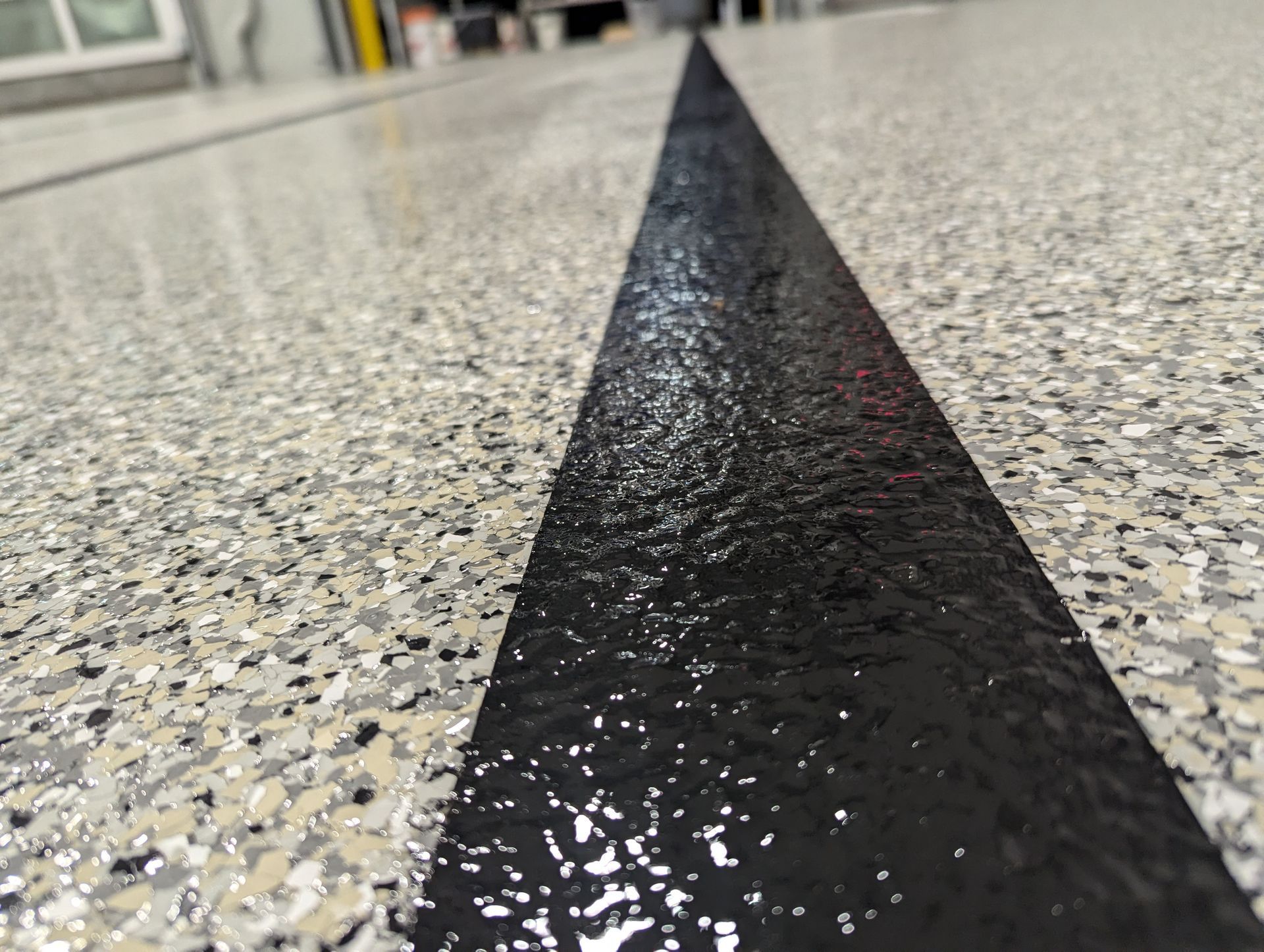 A close up of a black line on a gray and white floor.