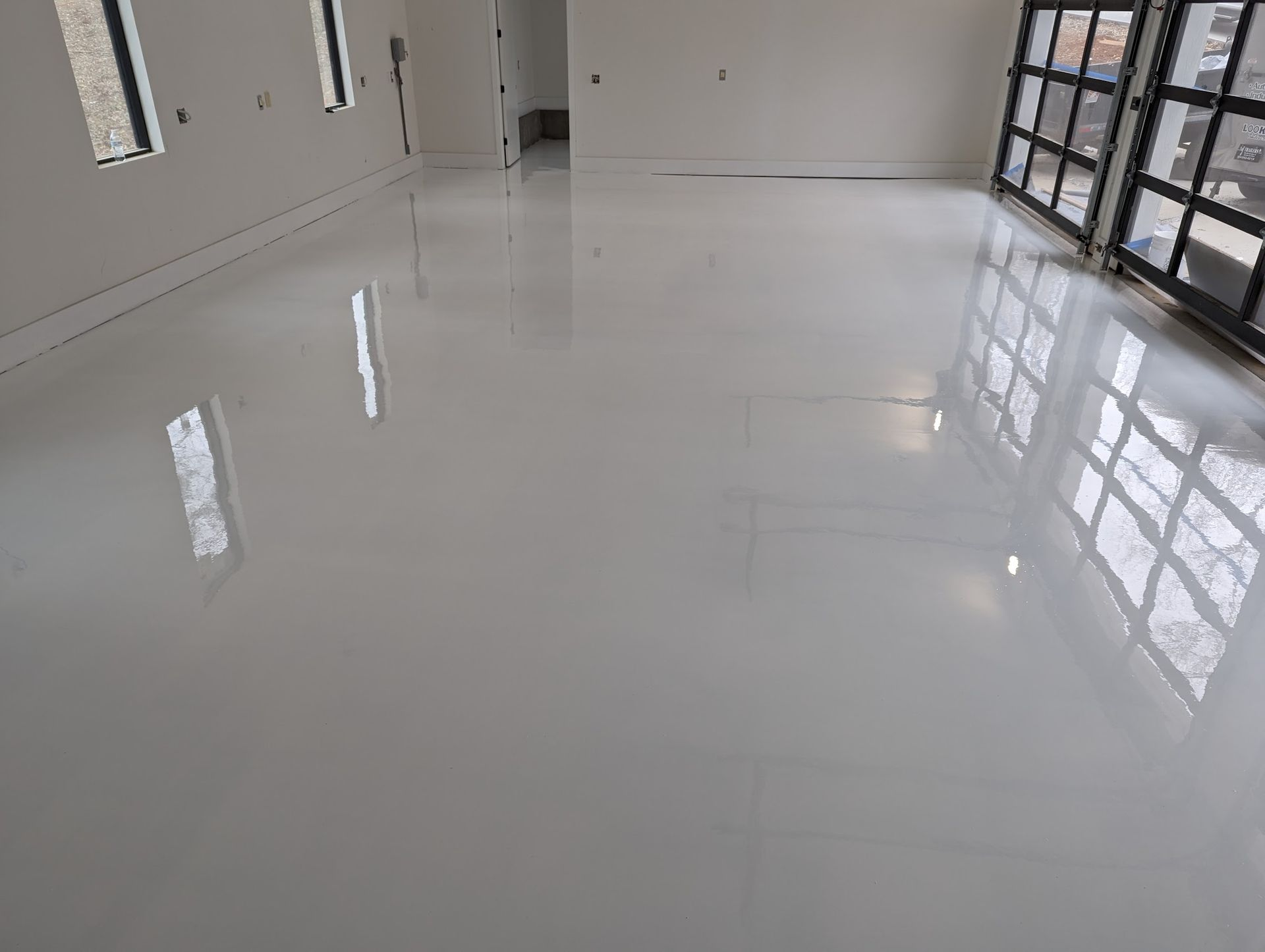 Empty glossy white room with large windows and reflections on the floor