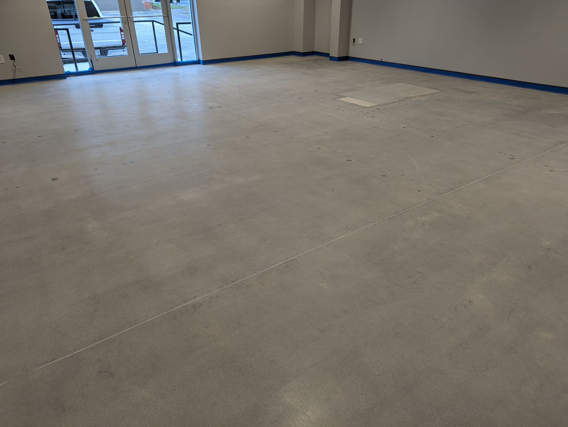 A large empty room with a concrete floor and a door.