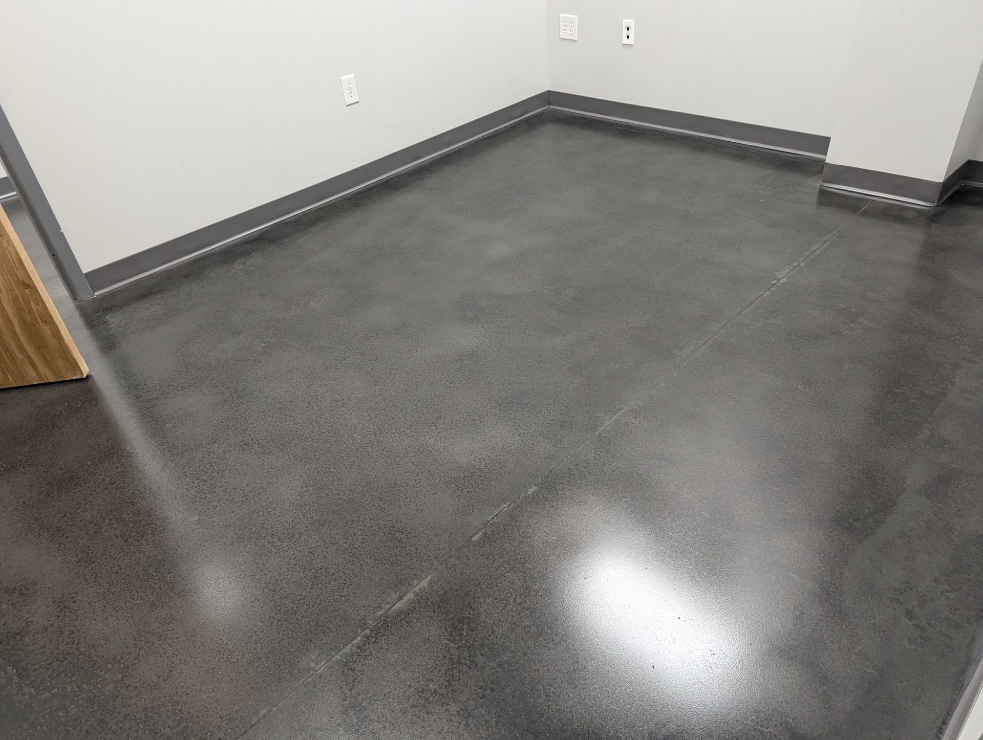 Polished gray concrete floor in a room with gray trim and light gray walls.