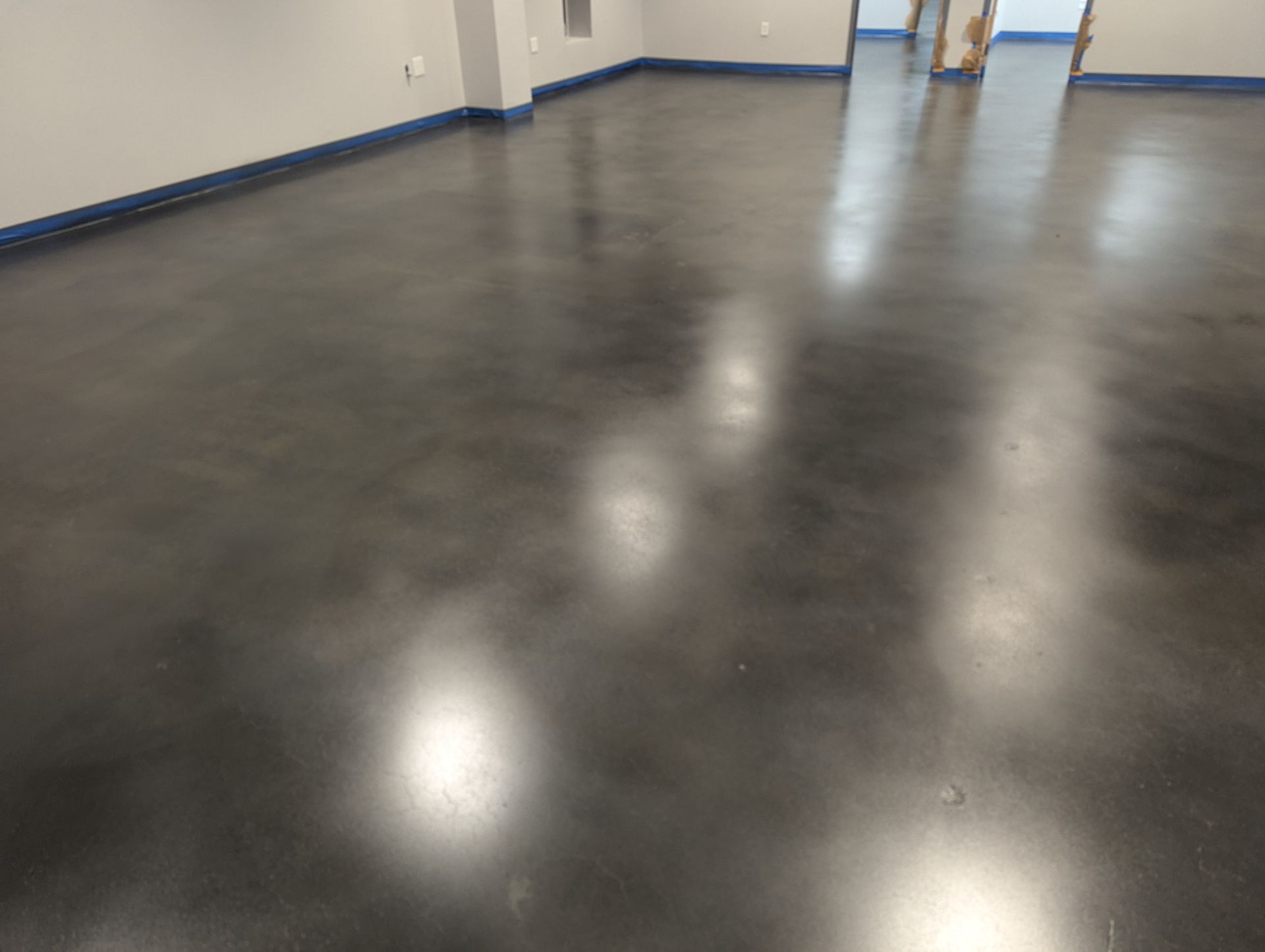 A shiny concrete floor in a room with a door.