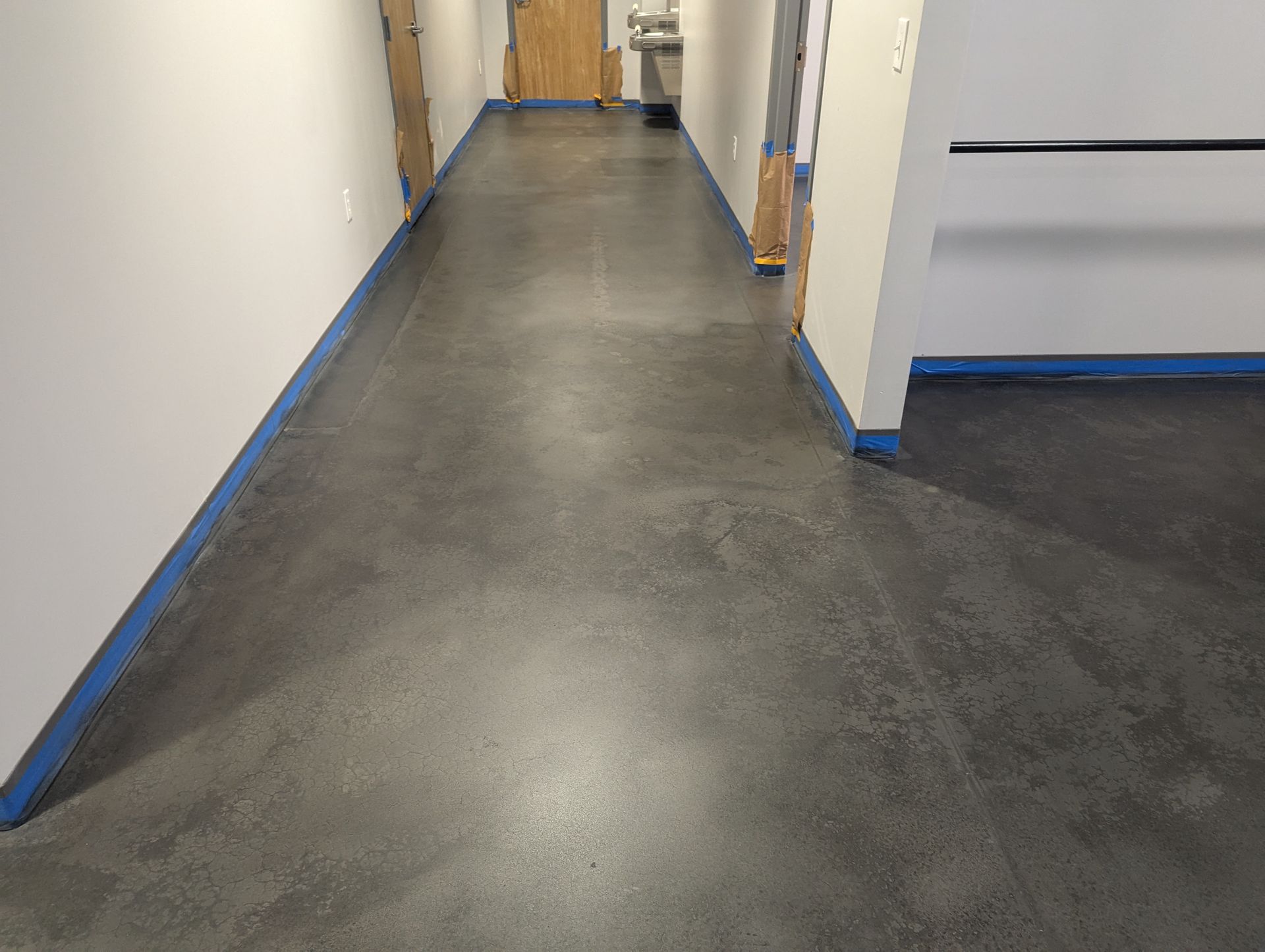 A long hallway with a gray floor and blue trim.