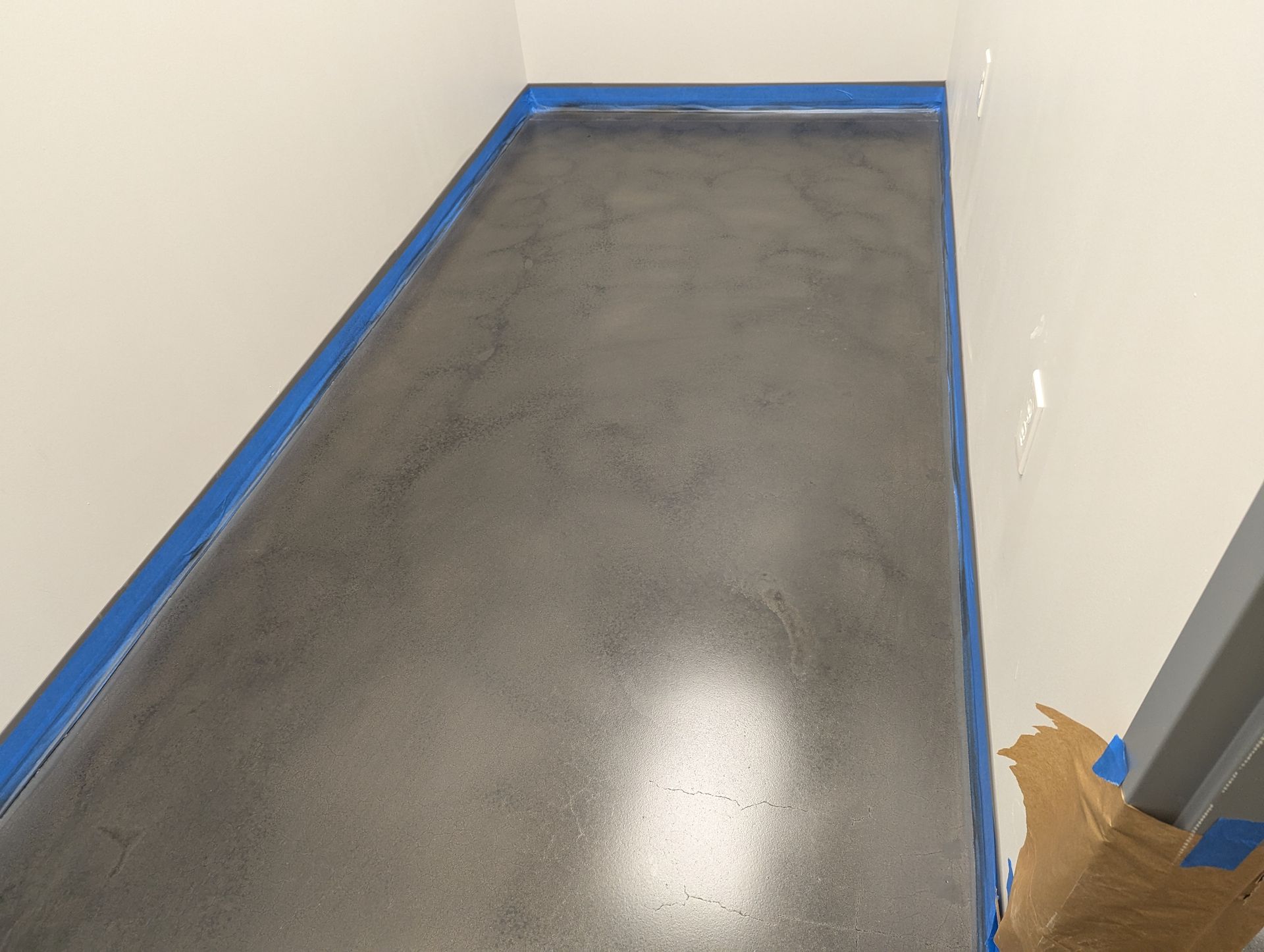 A concrete floor in a room with blue tape on it.