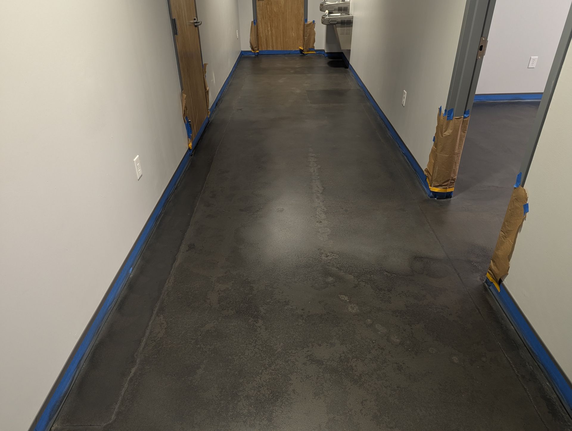 A long hallway with a black floor and blue trim.
