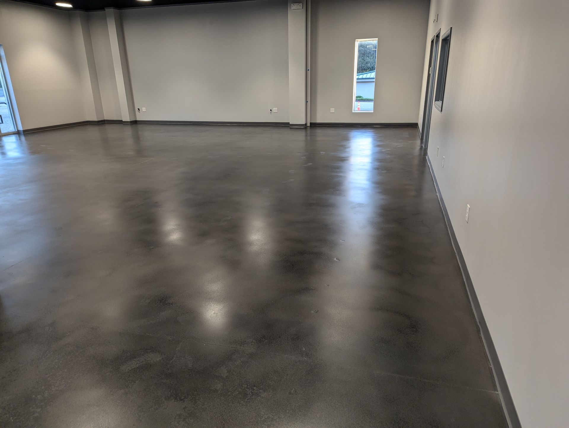A large room with a shiny concrete floor and white walls.