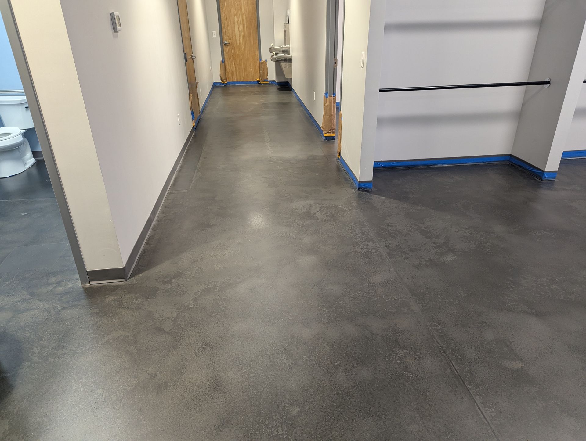 A long hallway with a concrete floor and a toilet.