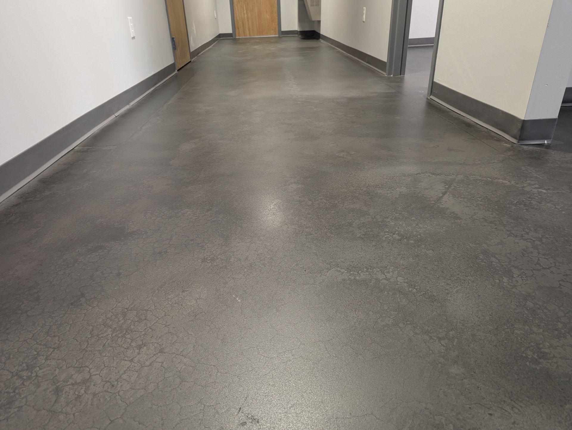 A person is walking down a hallway with a concrete floor.