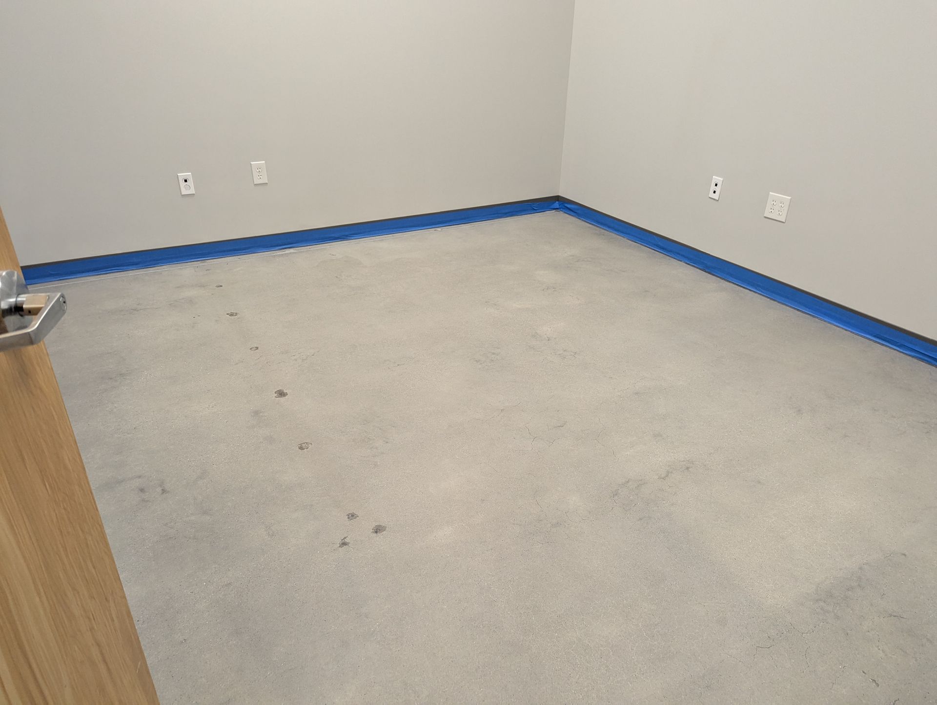 An empty room with a gray carpet and blue trim.