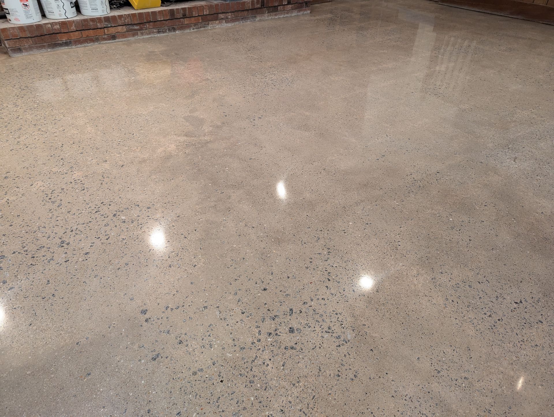 A polished, light-colored concrete floor with exposed aggregate, reflecting overhead lights.