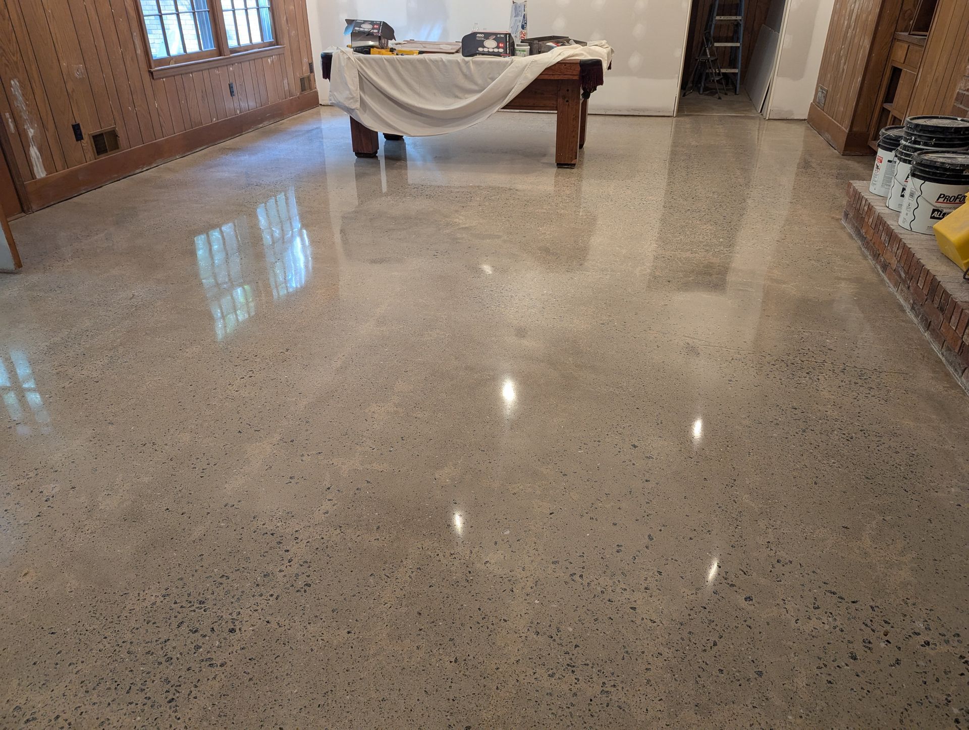 A pool table is sitting on a shiny concrete floor in a room.