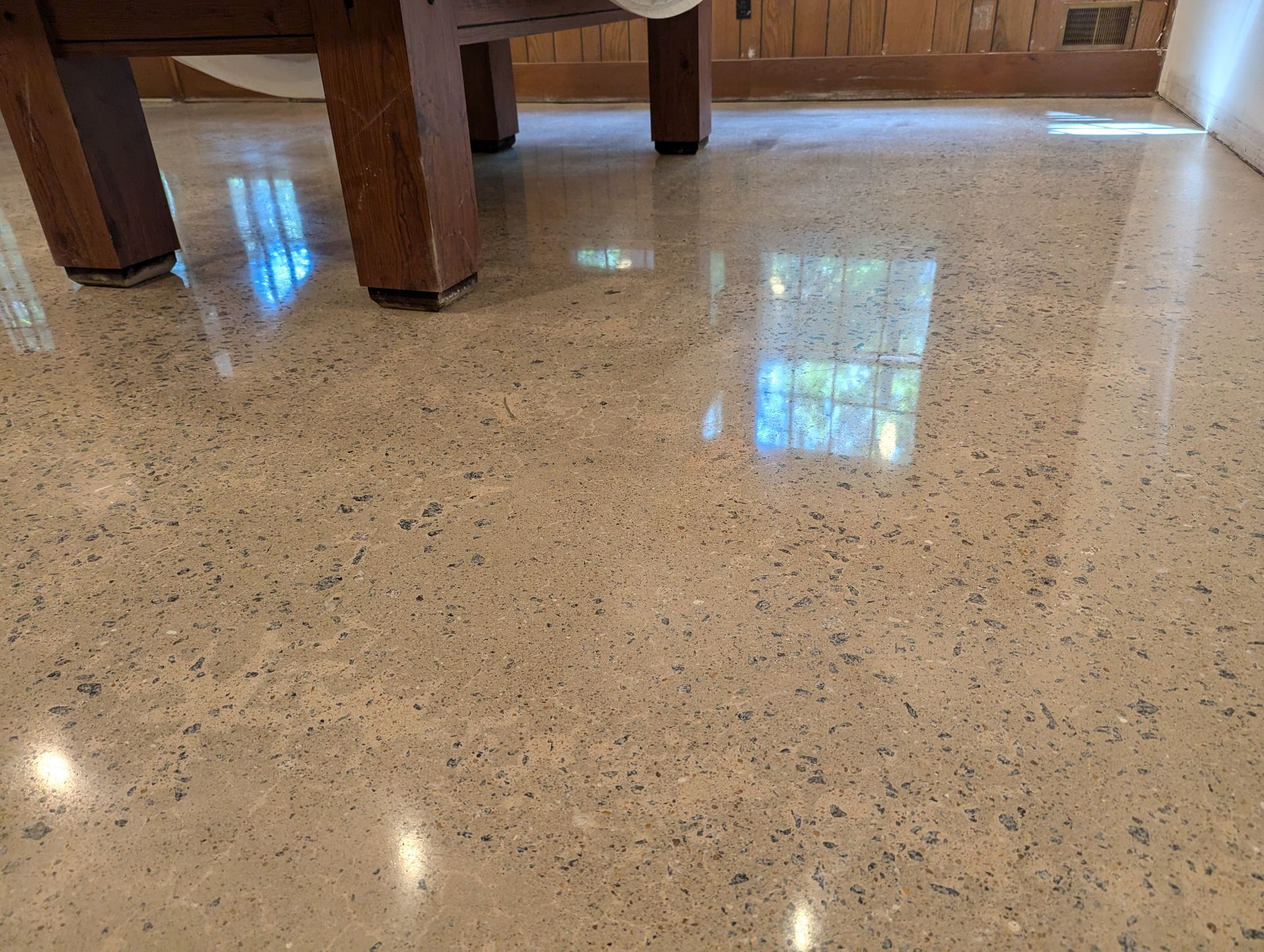 A shiny concrete floor with reflections of windows in it.