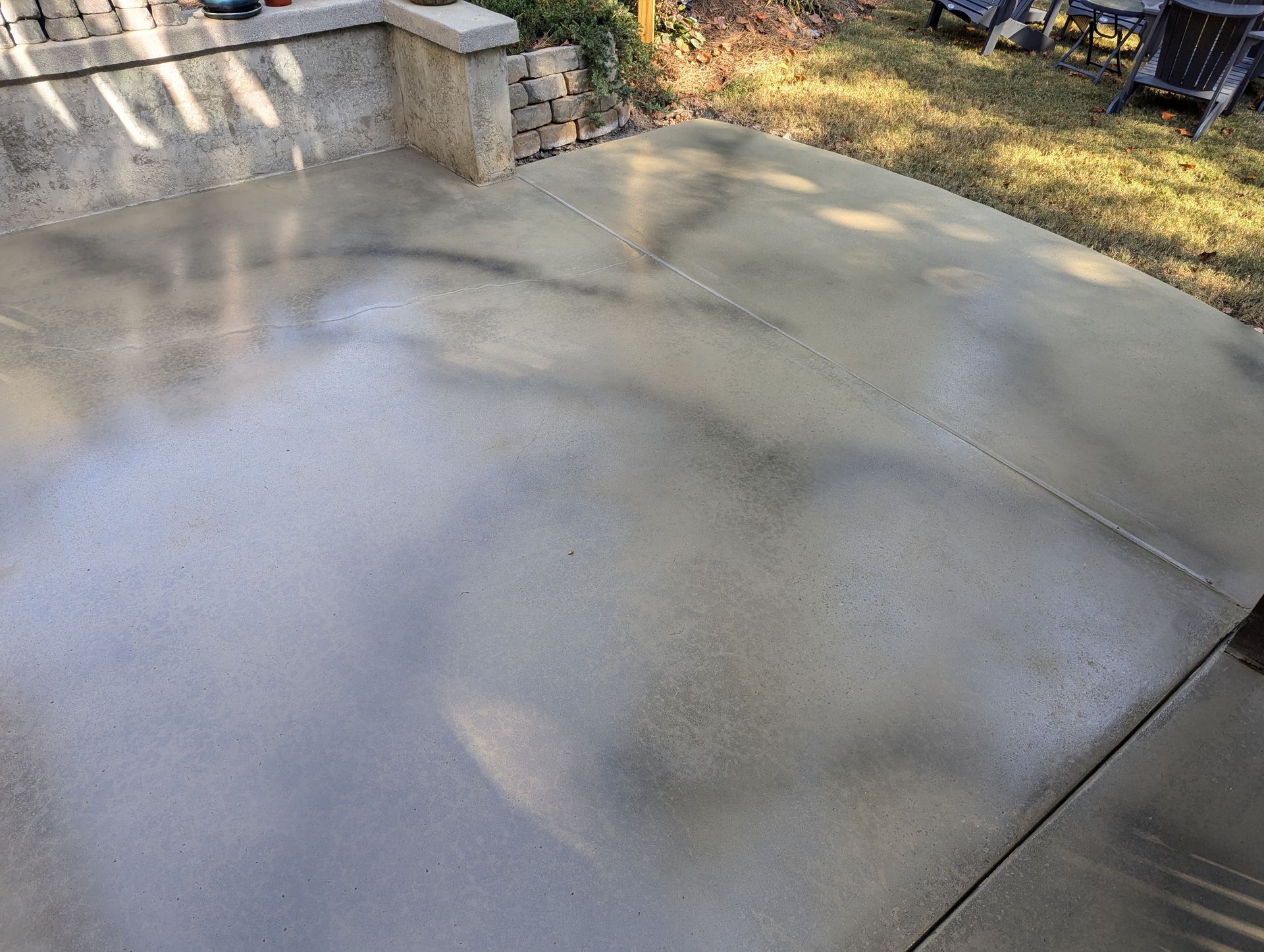 A concrete patio with a table and chairs in the background.
