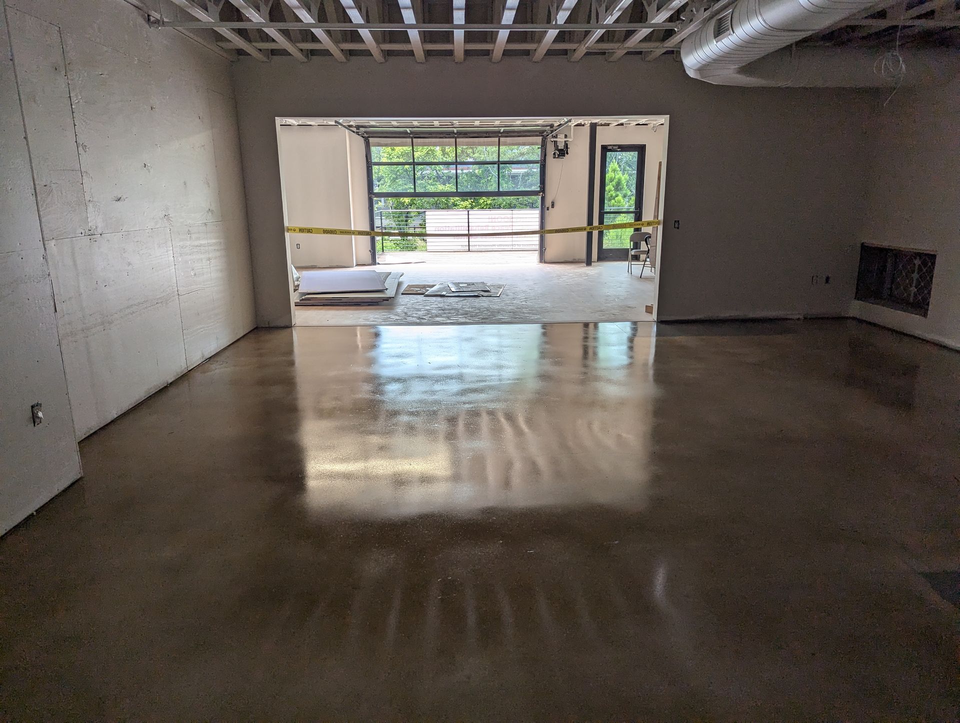 A large empty room with a concrete floor and a garage door.