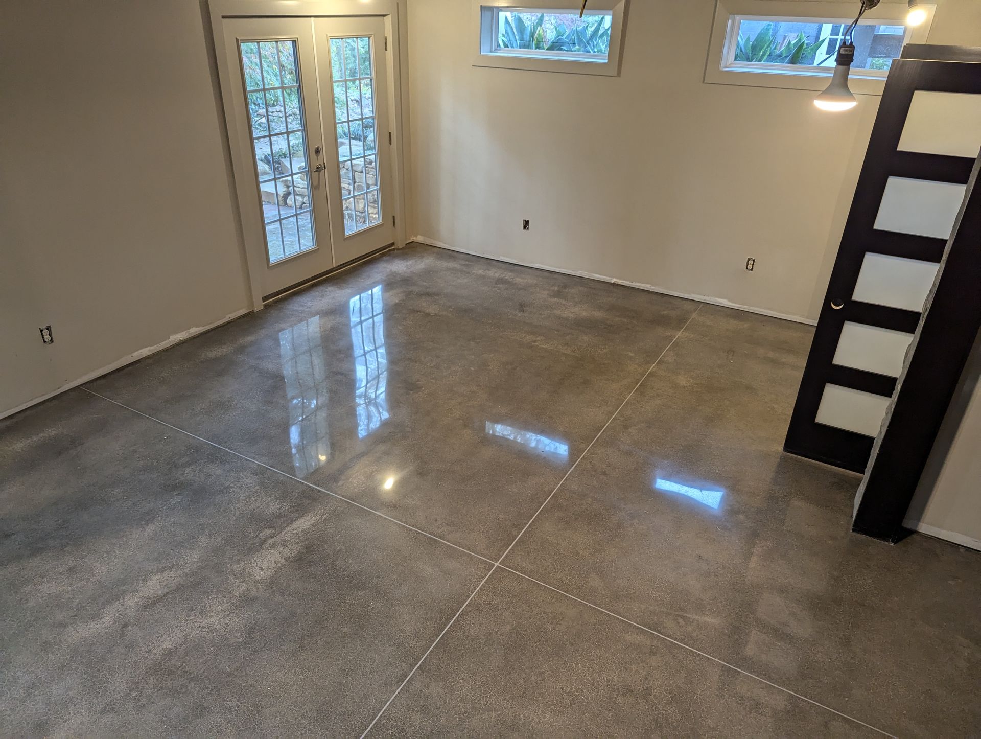 A room with a shiny concrete floor and a black door.