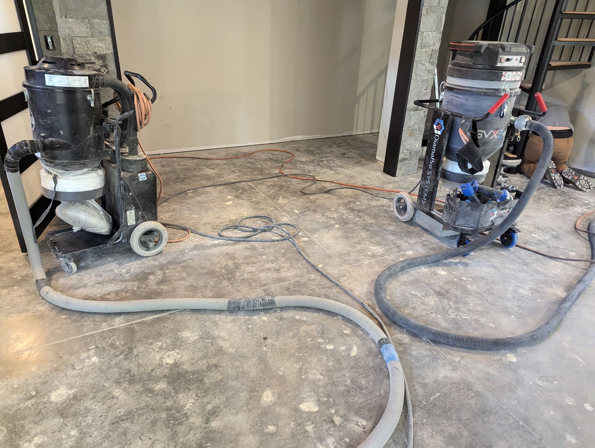 Two flooring equipment are sitting on a concrete floor in a room.