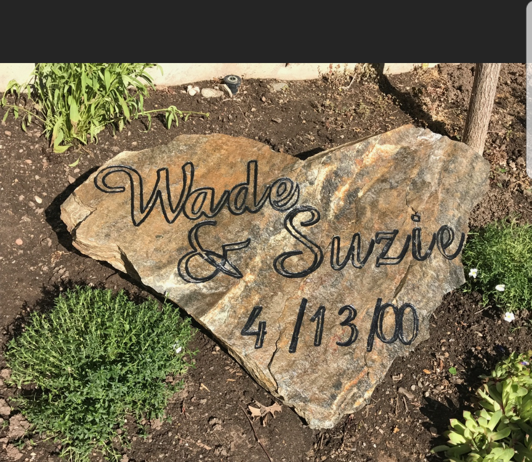 A large rock with the names wade and suzie written on it is sitting in the dirt.
