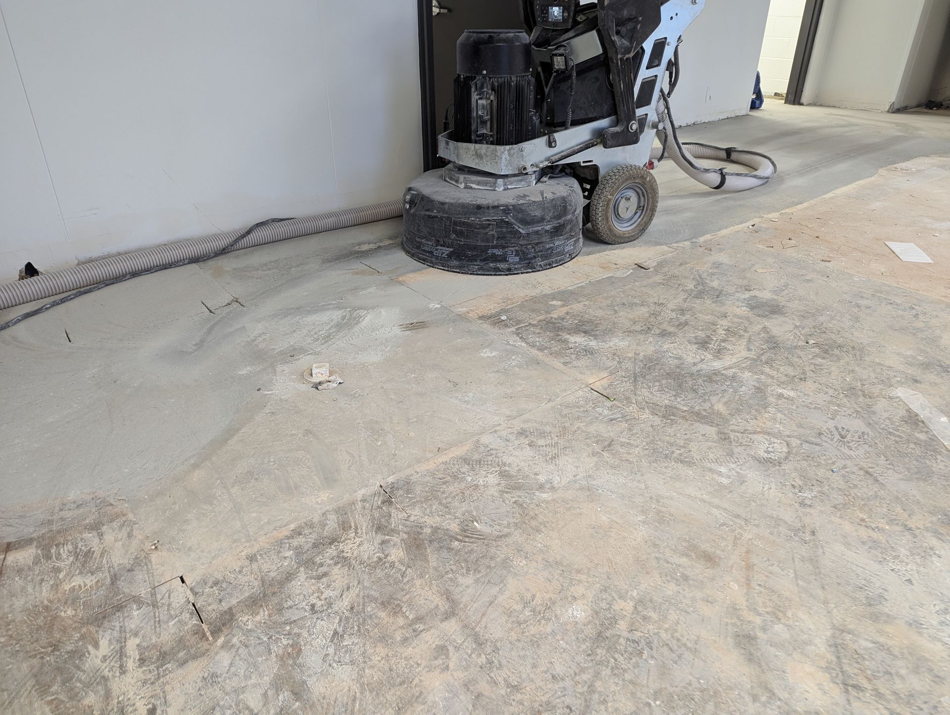 A machine is grinding a concrete floor in a building.