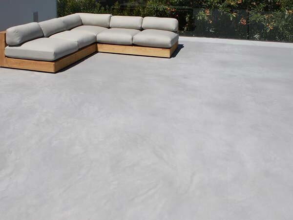 A sectional couch is sitting on a concrete floor.