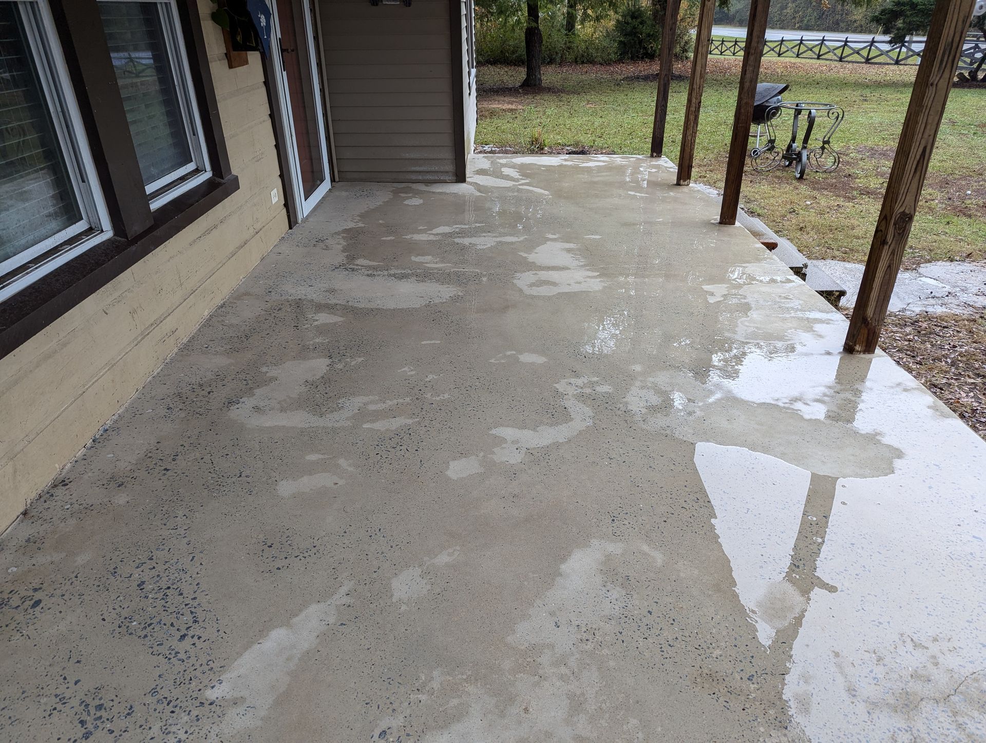 A concrete patio with a reflection of a house in it