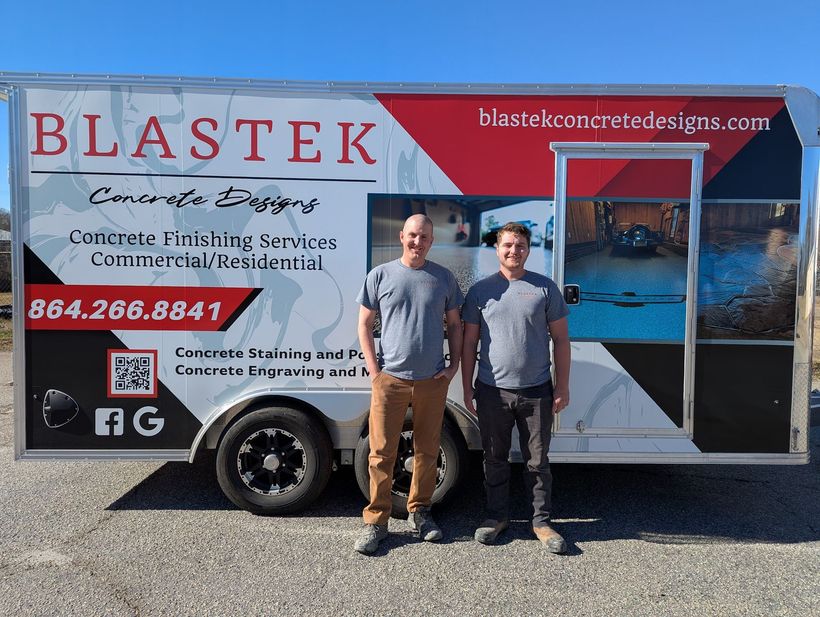 Two men are standing in front of a blastek trailer