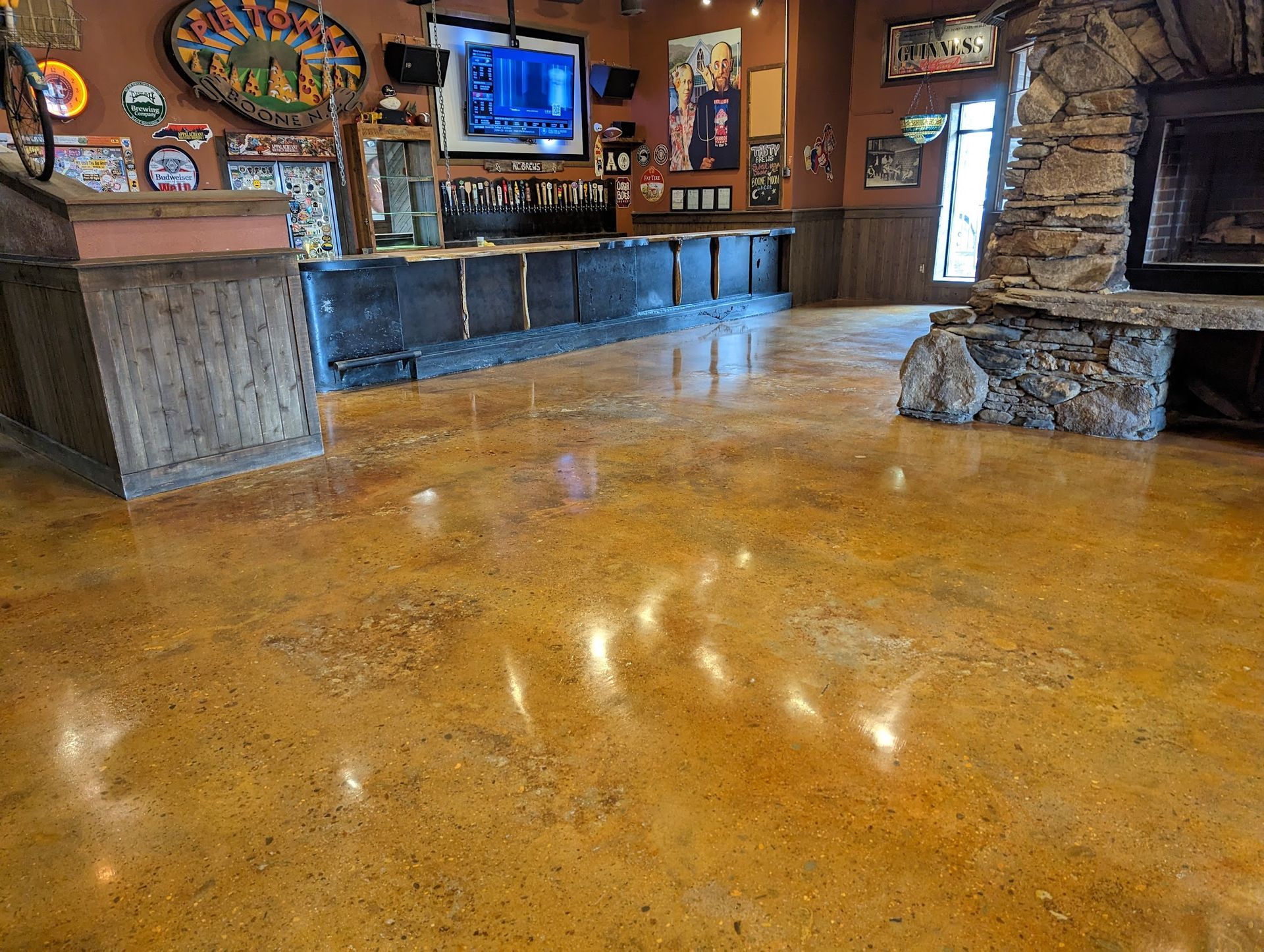 A large room with a concrete floor and a stone fireplace.
