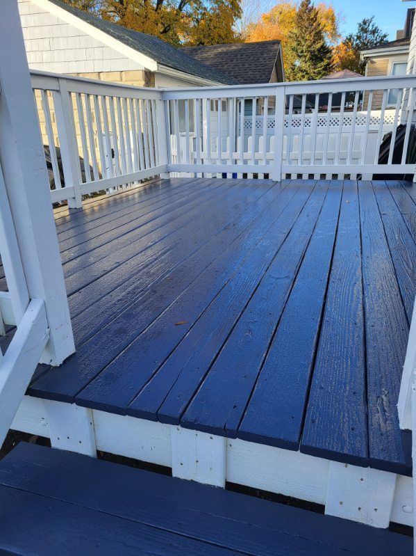 White-railed wooden deck with dark blue floorboards, viewed from the corner in daylight