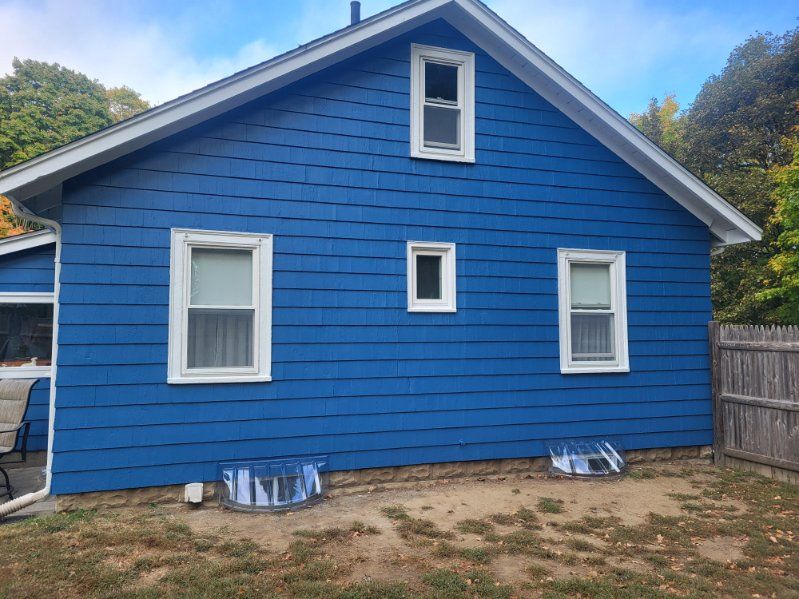 Blue house exterior with white trim and small windows under a peaked roof